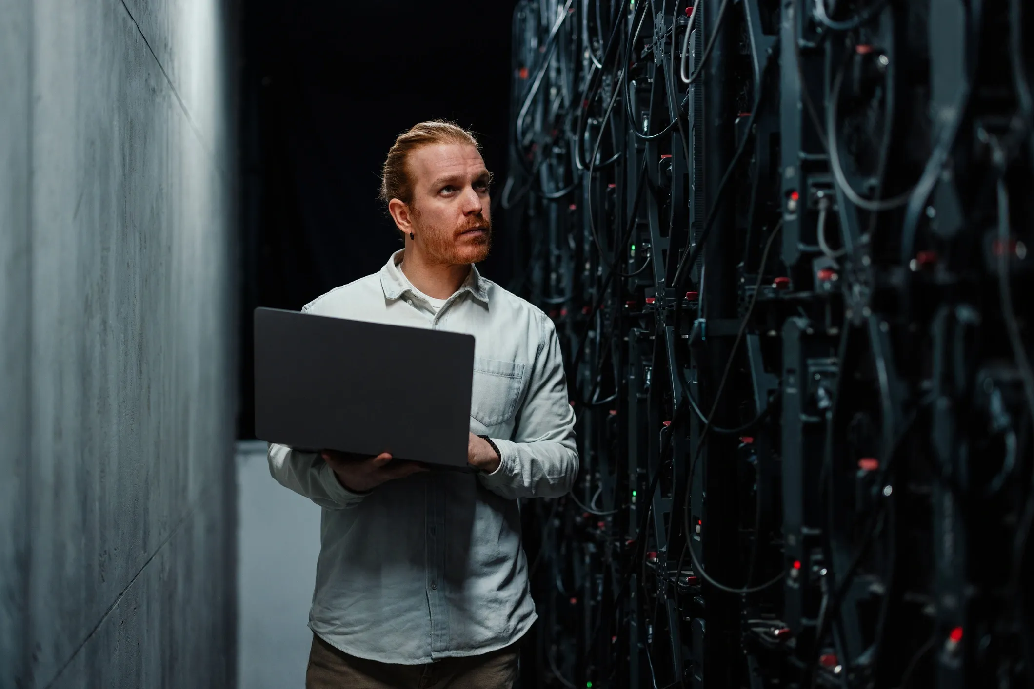 Technician with laptop reviewing server equipment